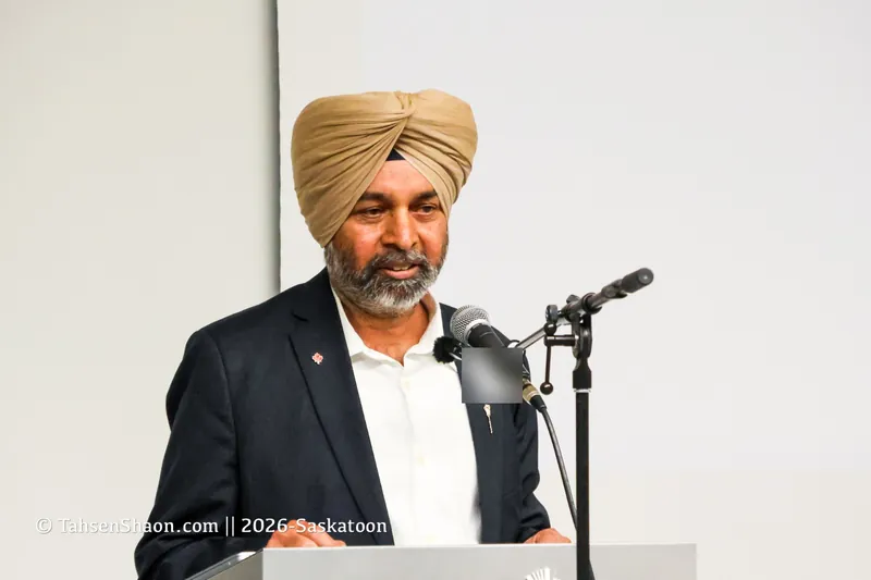 A speaker in a dark jacket and white shirt at the podium